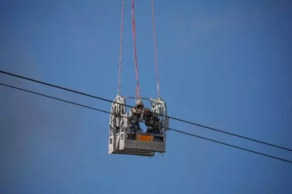 Helikoptere bağlı sepetle elektrik iletim hatlarına bakım yaparken ölüme meydan okuyorlar