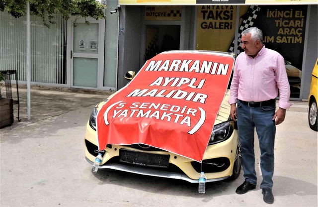 Aldığı lüks aracı işyerinin önüne koyup, üzerine 'Markanın ayıplı malıdır, 5 yıldır yatmakta' yazdı