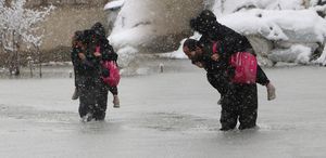 Evinin önünde biriken su nedeniyle çocuklarını sırtında taşıyor