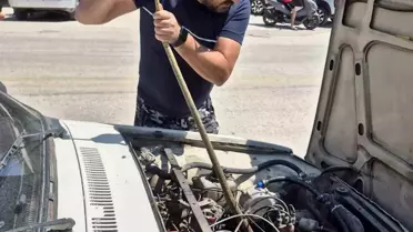Aracın motoruna giren yılanı elindeki sopayla çıkardı