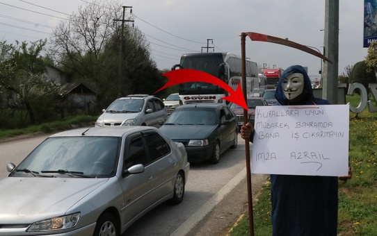 Bir elinde tırpan bir elinde pankartla trafiğe çıkıp sürücüleri uyardı