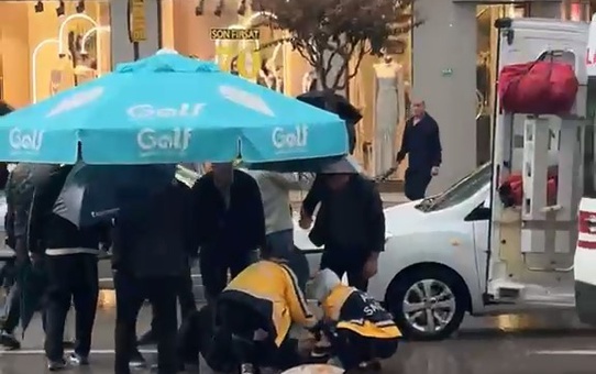 Bursa Osmangazi'de otomobil yayaya çarptı, çevredekiler yağmurda şemsiye tuttu