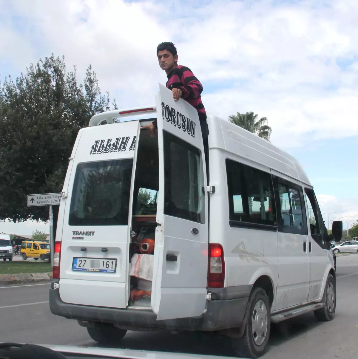 Bagaj Kapağında "Allah Korusun" Yazılı Bir Midibüsün Arka Kapısını Açarak Seyahat Eden Bir Kişi...
