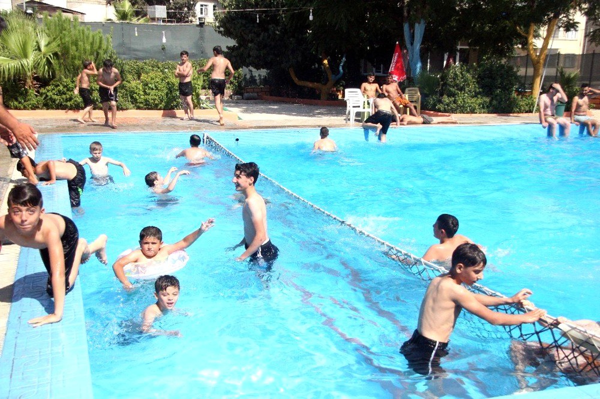 Gençler havuzda yüzerek serinliyor