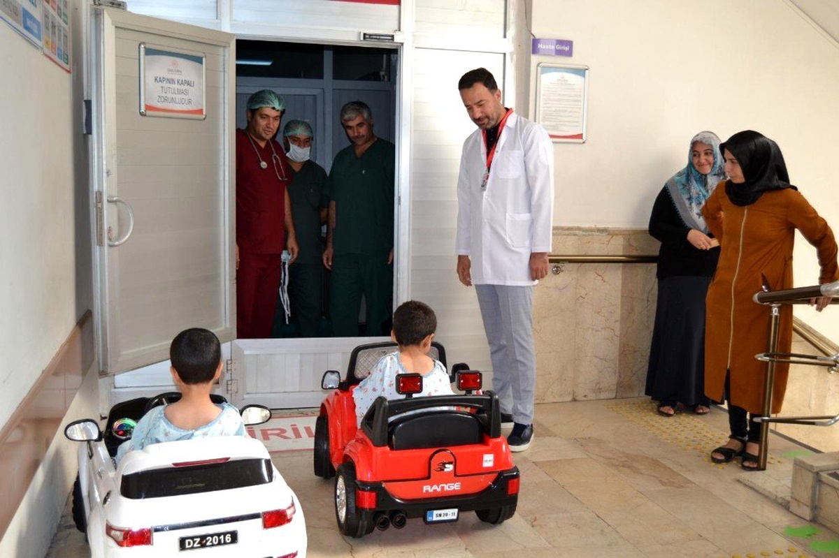 Çocuklar gülerek bindikleri akülü arabayla ameliyata giriyor