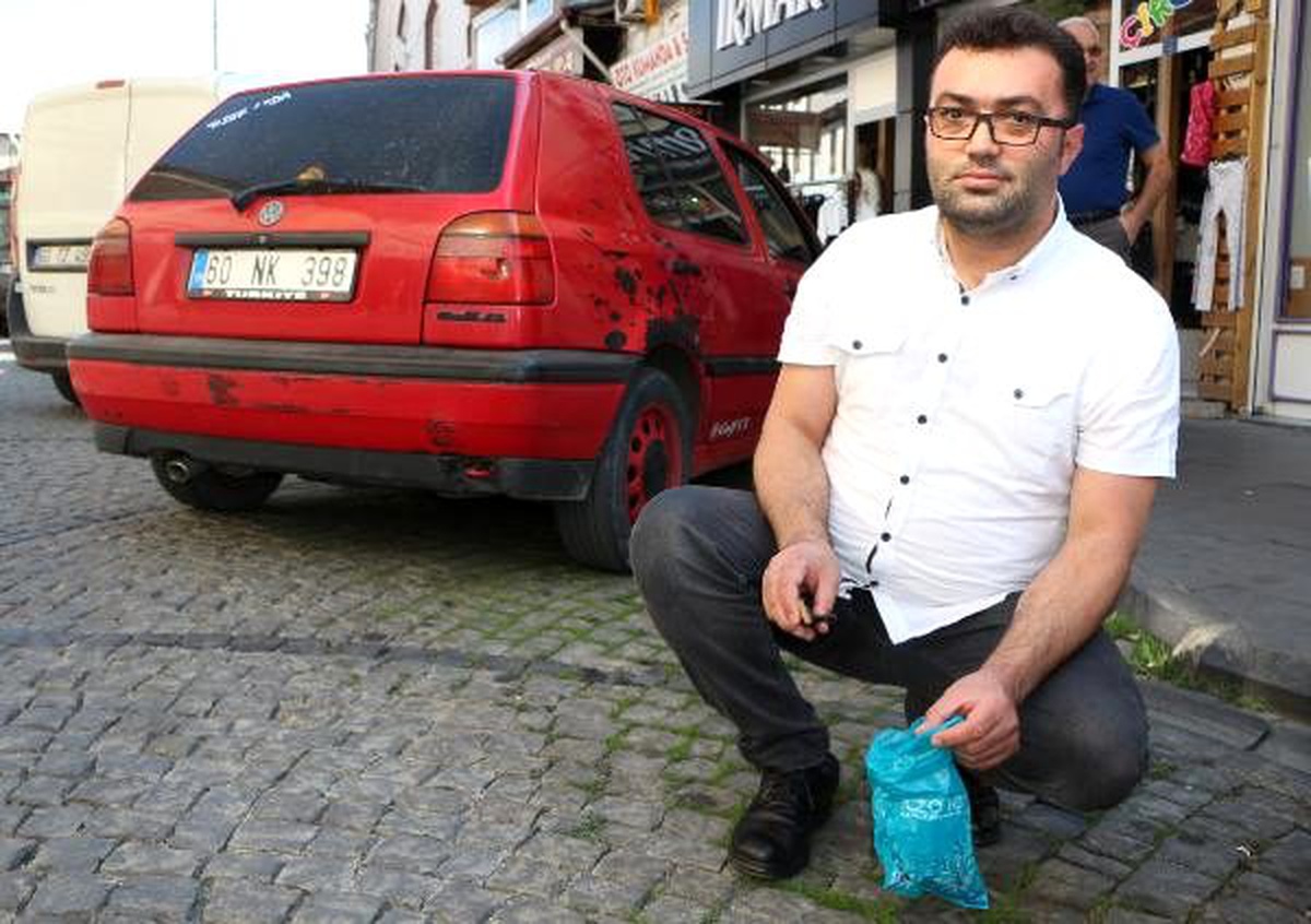 Sokaktaki sigara izmaritlerini makasla topluyor