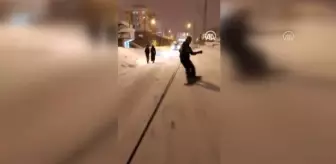 Van'ın karlı sokaklarında snowboard yaptı