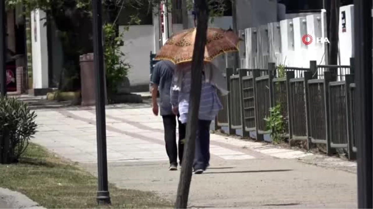 Sokağa çıkan yaşlılardan sıcağa karşı şemsiyeli önlem