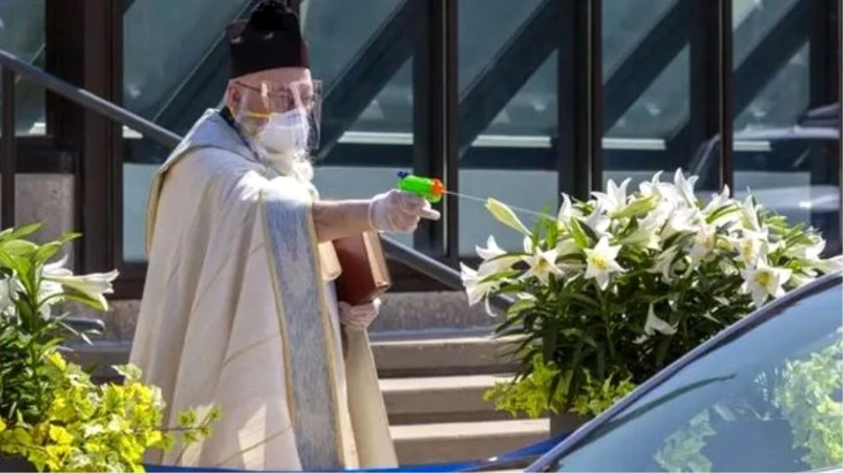 ABD\'de sosyal mesafeyi gözeten rahip, ziyaretçilere oyuncak tabanca ile uzaktan kutsal su sıktı