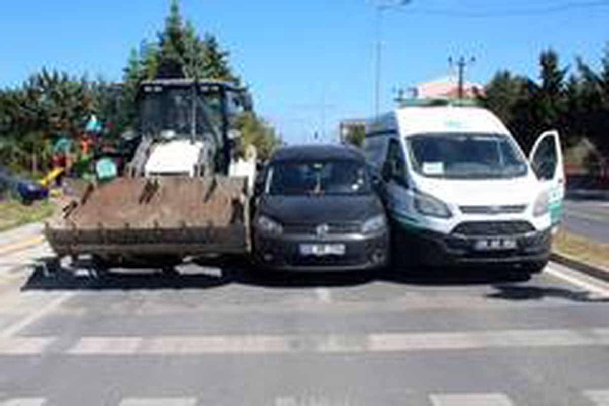 Otomobil, kırmızı ışıkta bekleyen iş makinası ve cenaze aracının arasından geçmeye çalışırken...