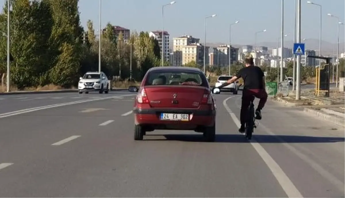 Otomobilin aynasına tutunan bisikletlinin, tehlikeli yolculuğu