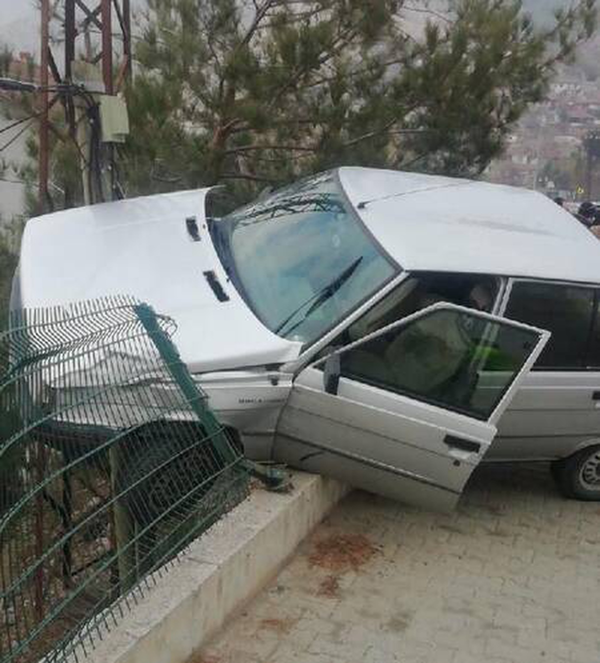 Bir araç ve telefon direğine çarpan otomobil, duvarda asılı kaldı