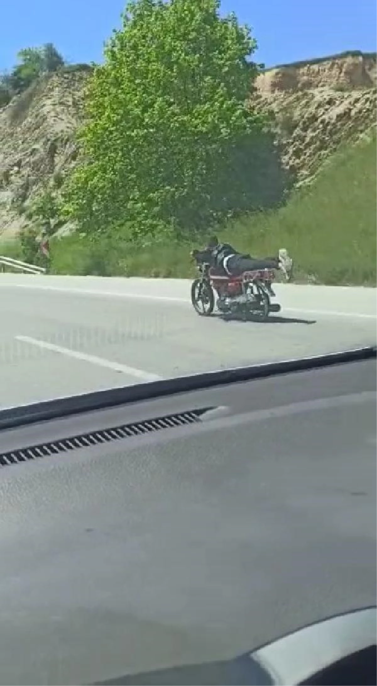 Üzerine uzandığı motosikletle tehlikeli yolculuk
