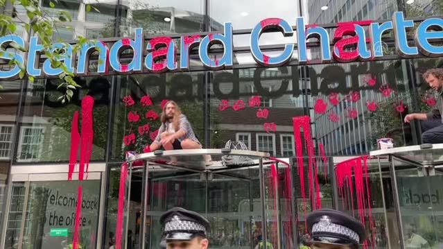 İngiltere'de çevreci grup fosil yakıtlara yatırımı protesto için banka binasını kırmızıya boyadı