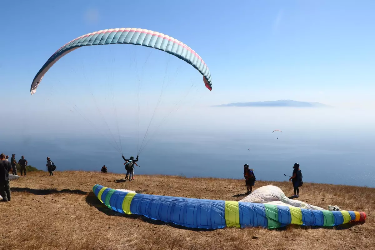 Mavi ve yeşilin tonları arasında yamaç paraşütü yapıyorlar