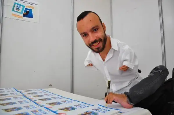 Ayağıyla yazdığı kitabını, okurları için ayağıyla imzaladı