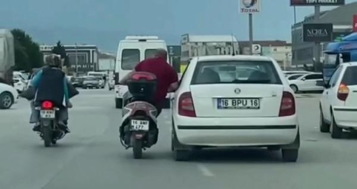 Motosikletli, otomobilin kapısına tutunarak sürücüyle sohbet etti