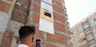 Bina duvarında asılı kalan mutfak dolabını gören fotoğrafını çekiyor