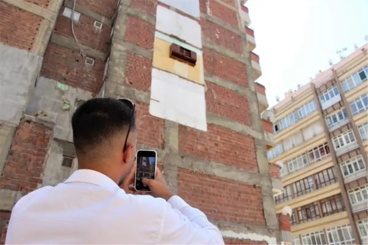 Bina duvarında asılı kalan mutfak dolabını gören fotoğrafını çekiyor