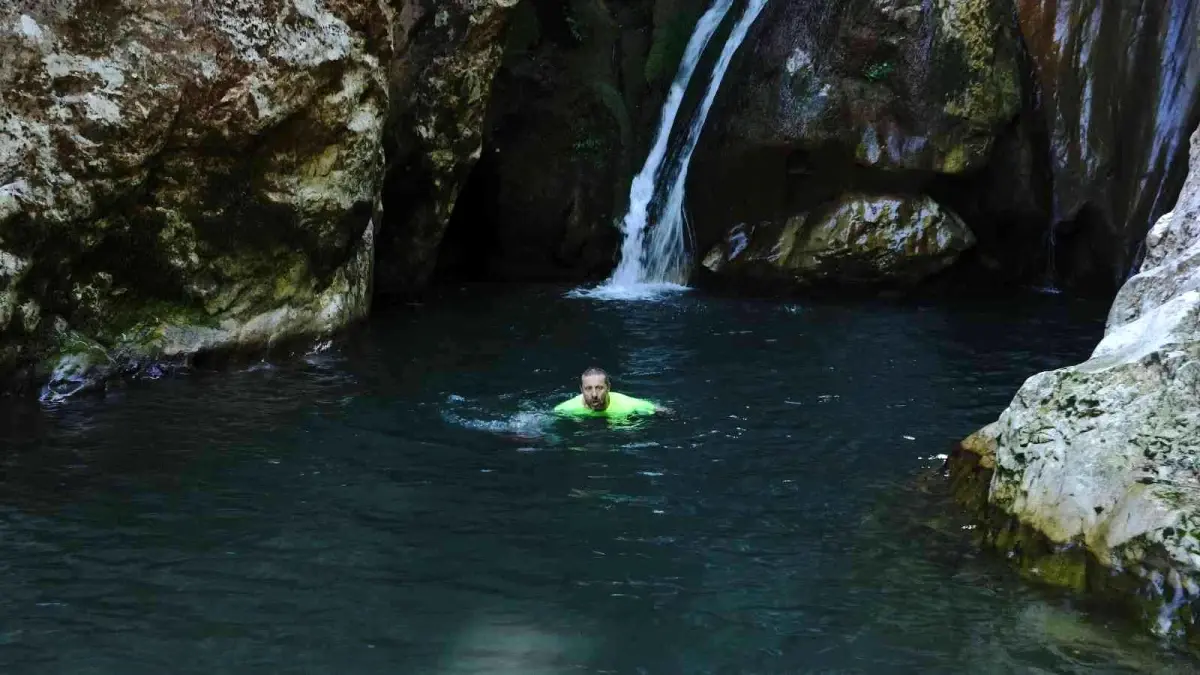 Doğa harikası şelaleleri tanıtmak için soğuk havaya aldırış etmeden buz gibi suda yüzdü
