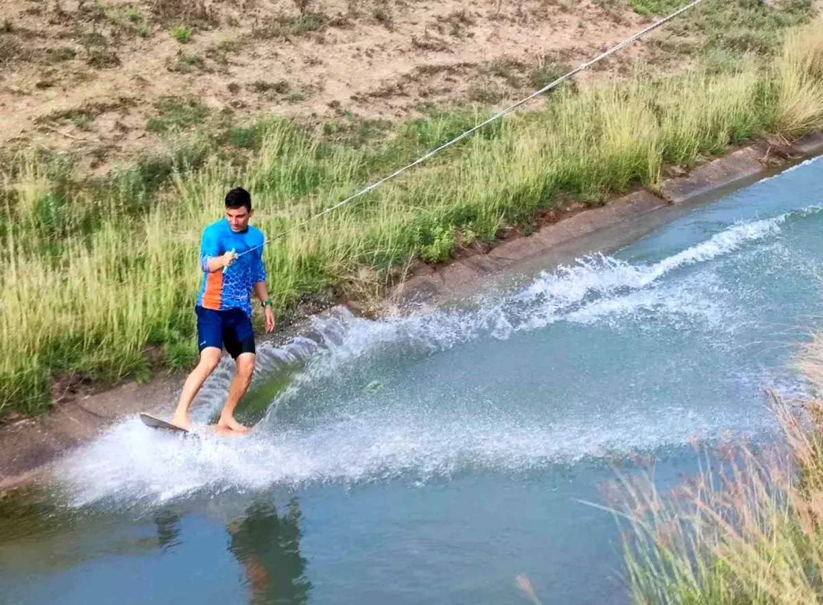 Adana\'da genç, kendi yaptığı sörf tahtasıyla sulama kanalında sörf yapıyor