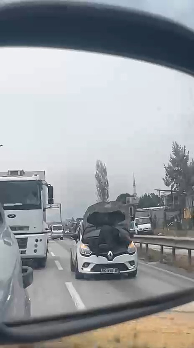 Bursa'da kaputu açık otomobilin motoru üzerinde giden kişi kamerada