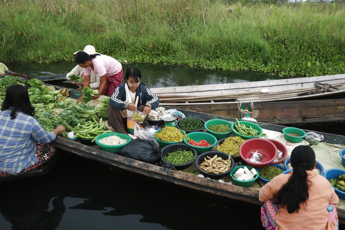 Myanmar\'ın Inle Gölü\'ndeki yüzen pazarda satıcılar teknelerde taze gıda satıyor